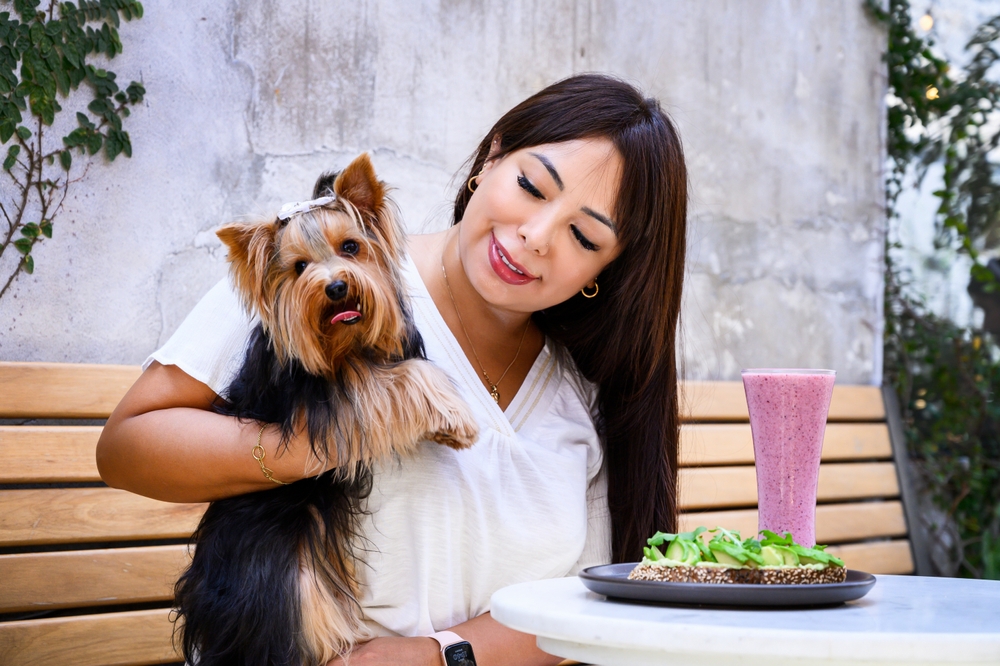 Cheerful,Lady,With,A,Dog,Sitting,In,An,Outdoor,Cafe,