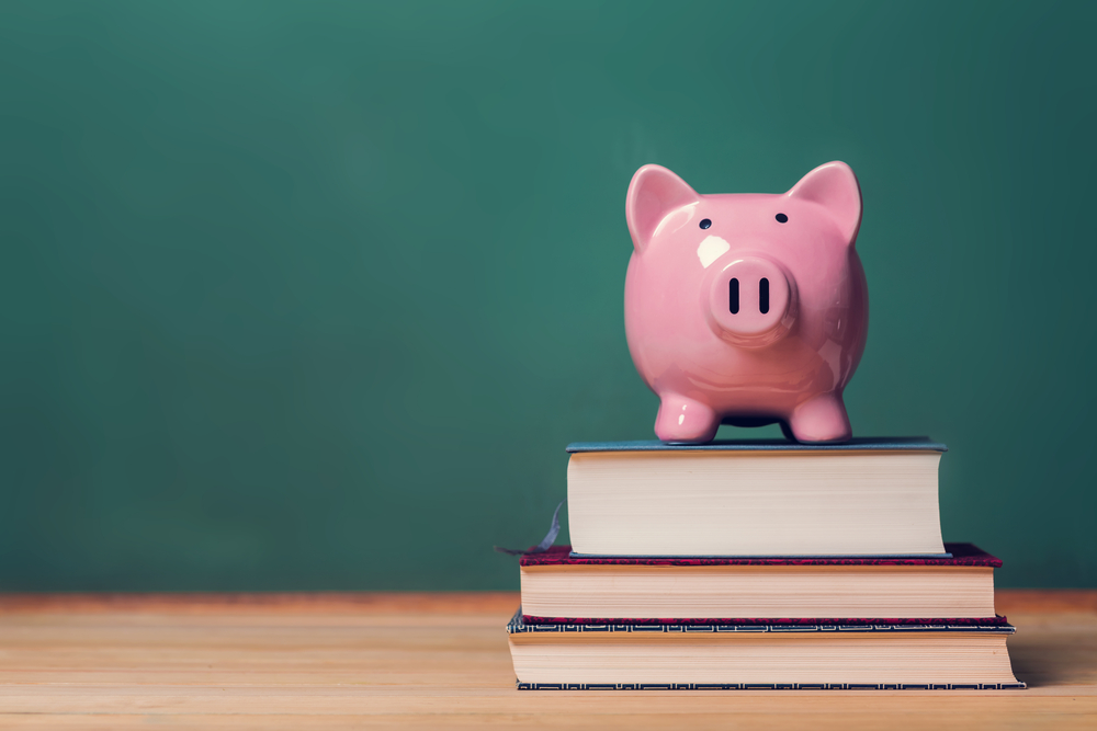 Pink,Piggy,Bank,On,Top,Of,Books,With,Chalkboard,In